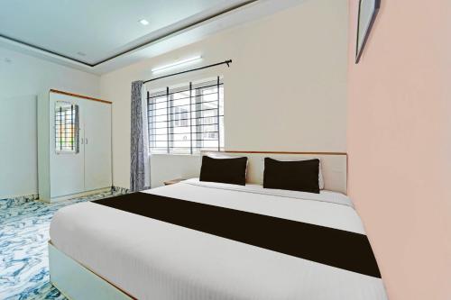 a bedroom with a white and black bed with a window at Super Hotel O Vijaynagar Road Formerly Anmol Peace Stay in Ooty