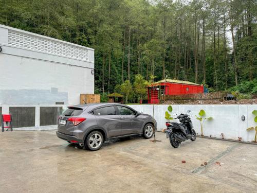 a car parked next to a motorcycle in a parking lot at Diyanis Glamping Sekipan Tawangmangu Mitra RedDoorz in Tawangmangu