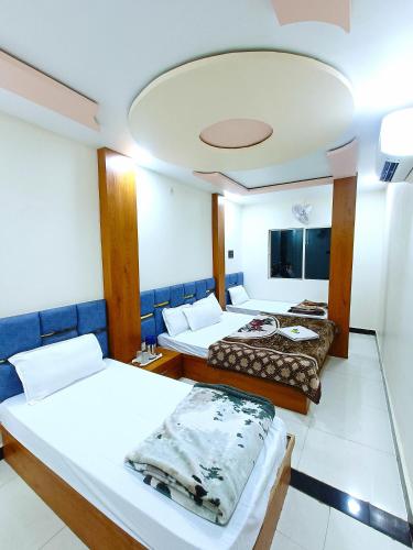 a hotel room with two beds and a ceiling at Hotel Shreem in Ujjain