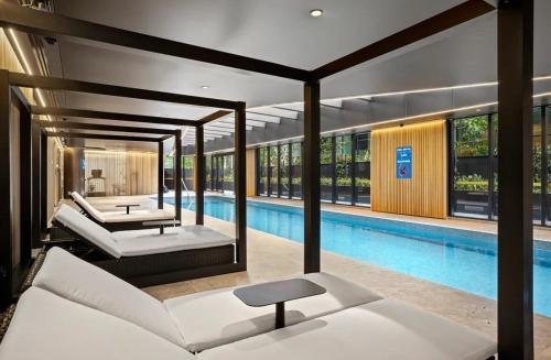 a swimming pool with two beds next to a swimming pool at Luxury 2B2B Albert Park Lakeside Apartment with Pool, Gym, Sauna & CarPark in Melbourne