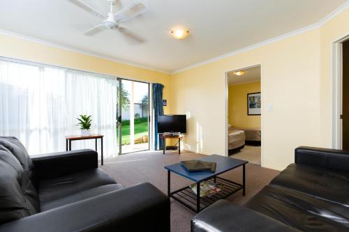 uma sala de estar com um sofá e uma televisão em Elliotts Kapiti Coast Motor Lodge em Paraparaumu Beach