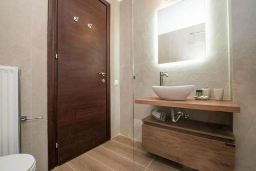 a bathroom with a sink and a toilet and a mirror at Artemis Oasis Villa with private Pool in Khartáta