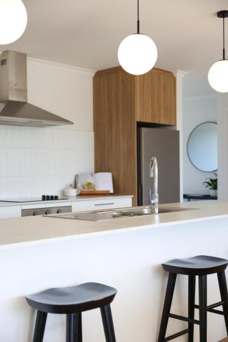 a kitchen with two bar stools and a sink at Berryfields Luxury Gem - New Home Richmond in Nelson