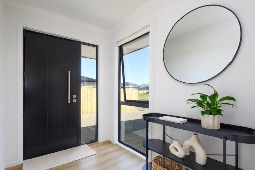 a hallway with a black door and a mirror at Berryfields Luxury Gem - New Home Richmond in Nelson