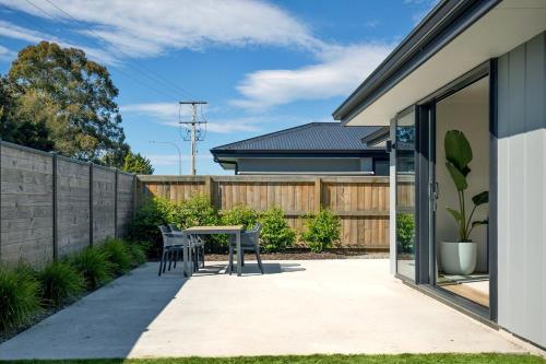 a patio with a table and chairs in a backyard at Berryfields Luxury Gem - New Home Richmond in Nelson