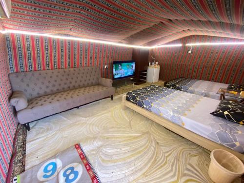 a room with two beds and a couch and a tv at private farmhouse Tent Room in Al Rahba
