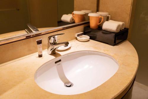 a white sink in a bathroom with a mirror at Ramada Plaza By Wyndham Fuzhou South in Fuzhou