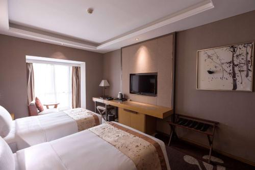 a hotel room with two beds and a television at Ramada Plaza By Wyndham Fuzhou South in Fuzhou