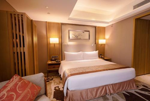 a hotel room with a large bed and a chair at Ramada Plaza By Wyndham Fuzhou South in Fuzhou