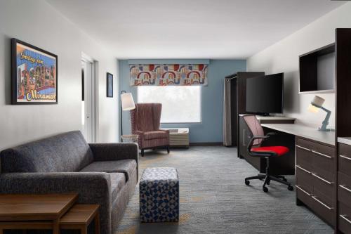 a living room with a couch and a desk with a computer at Home2 Suites by Hilton Miramar Ft. Lauderdale in Miramar