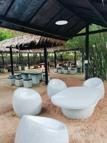 a group of white chairs and tables under a pavilion at สวนเพื่อคุณ รีสอร์ทแอนด์แคมป์ปิ้ง in Ban Don Wan
