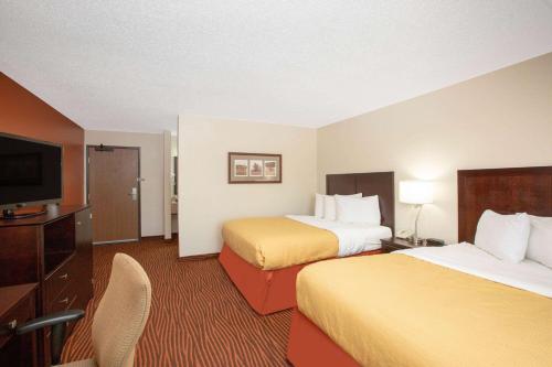 a hotel room with two beds and a flat screen tv at AmericInn by Wyndham Muscatine in Muscatine