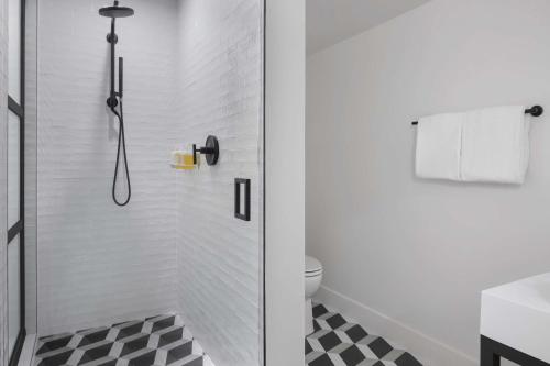 a bathroom with a shower with a black and white floor at The Lum Hotel Los Angeles Stadium District in Inglewood