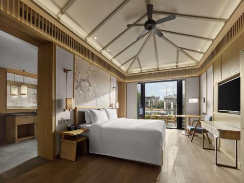 a bedroom with a white bed and a desk at Hilton Suzhou New District in Suzhou