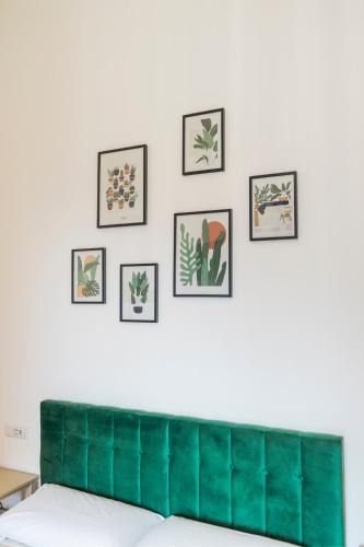 a green velvet couch on a white wall with framed pictures at Lia's room - Il Monticello in Positano