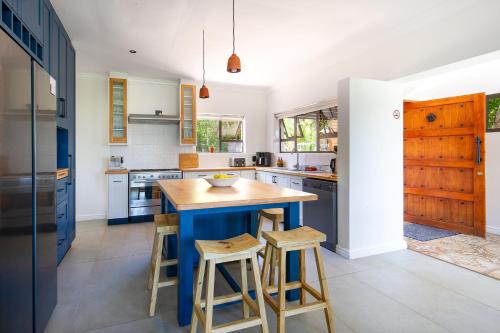 a kitchen with a blue island and stools at Seaside Family Villa in Wilderness