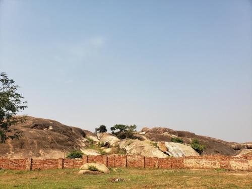 a brick wall in a field next to some rocks at Nyero Guesthouses in Kumi