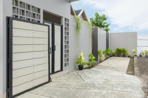 a white house with a gate and a driveway at Calma Jatimas Klayar Villa Sleman Jogja in Adi Sutjipto