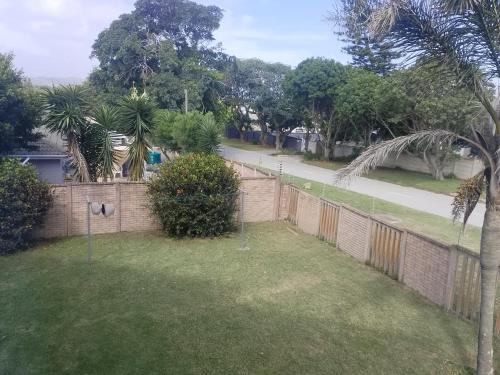 a fence in a yard with trees and a sidewalk at Croydon Cove in Port Alfred