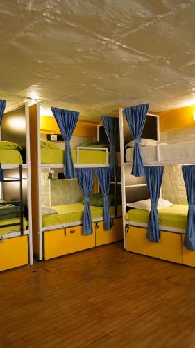 a room with three bunk beds with blue curtains at Julley Commune Rishikesh in Rishīkesh