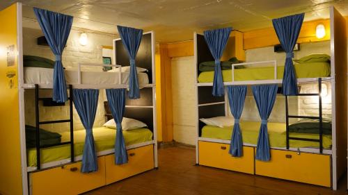 a room with two bunk beds with blue curtains at Julley Commune Rishikesh in Rishīkesh