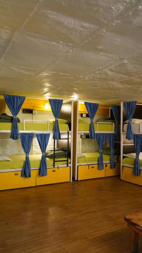 a room with four bunk beds with blue curtains at Julley Commune Rishikesh in Rishīkesh