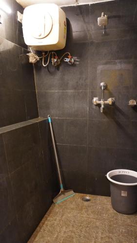 a bathroom with a toilet with a mop on the wall at Julley Commune Rishikesh in Rishīkesh