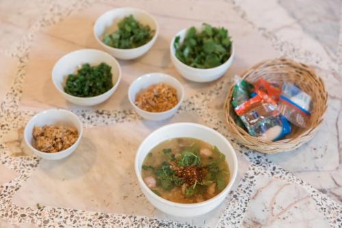 a group of bowls of soup and vegetables on a table at Hide & Seek River Villa in Ban Wang Wa (1)