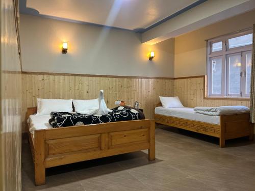 Un dormitorio con dos camas y una ventana. en Hotel Rigyal, en Lachung