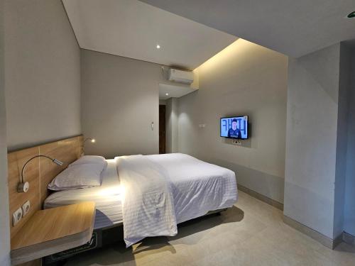 カリウランにあるHotel Kebon Kana Kaliurangのベッドと壁にテレビが掛かった寝室