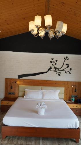 a bedroom with a large white bed with a chandelier at Julley Commune Rishikesh in Rishīkesh