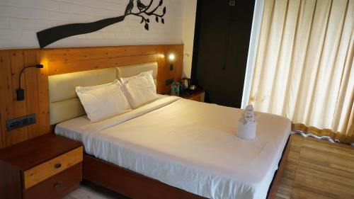 a bedroom with a large white bed with a wooden headboard at Julley Commune Rishikesh in Rishīkesh