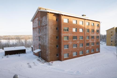 a large brick building in the snow in the snow at Guestly Homes - Nordic Studio in Luleå