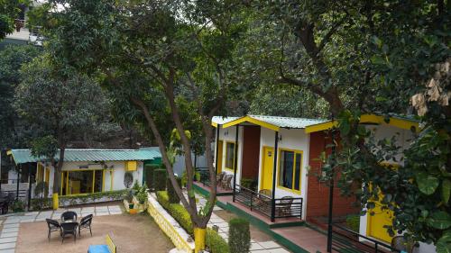 a yellow and white house with a patio and trees at Julley Commune Rishikesh in Rishīkesh
