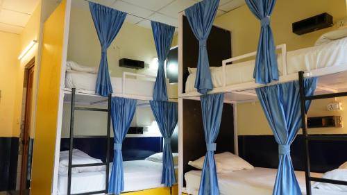 a group of bunk beds with blue curtains in a room at Julley Commune Rishikesh in Rishīkesh
