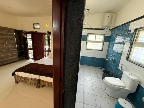 a bathroom with a bed and a toilet in it at Gadabanahalli Homestay in Vastāra