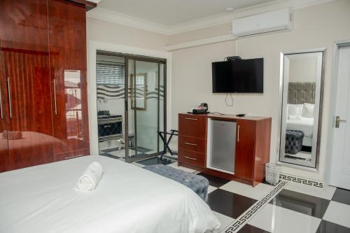 a bedroom with a white bed and a tv at Papiano Boutique Hotel in Bloemfontein
