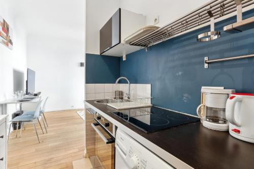 - une cuisine avec un évier et un mur bleu dans l'établissement Chic and comfortable studio near Paris, à Boulogne-Billancourt