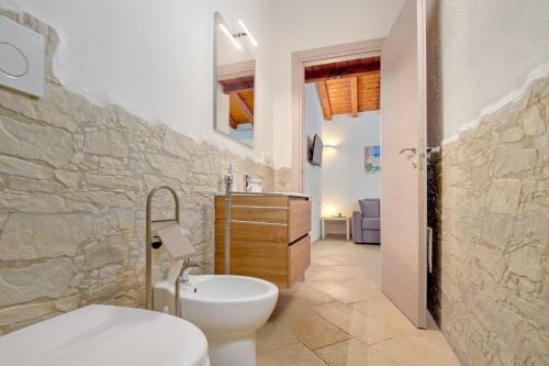 a bathroom with a white toilet and a stone wall at Stazzu Gallurese in Olbia
