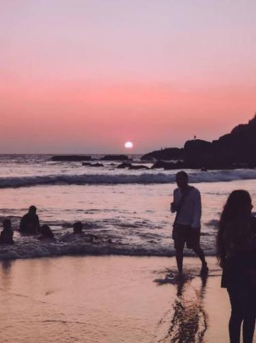 a group of people walking on the beach at sunset at Baga Beach Crystal in Baga