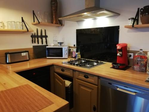 a kitchen with a stove top oven next to a microwave at Le logis du heron in Coulon