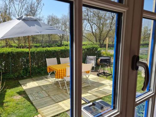 a view of a table and an umbrella from a window at Le logis du heron in Coulon