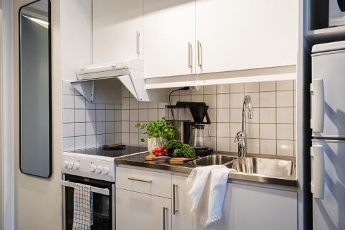 a kitchen with white cabinets and a sink at Guestly Homes - Cozy Studio in Luleå