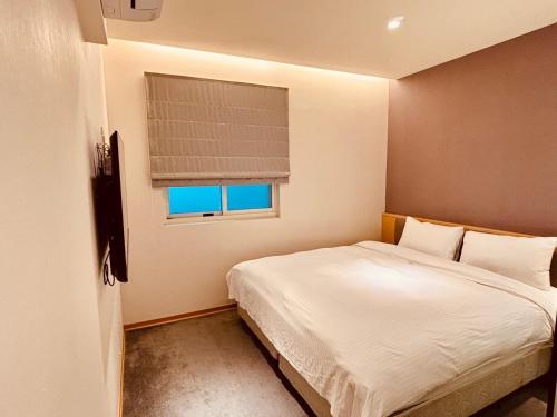 a small bedroom with a bed and a window at Michi Hotel - Zhongli in Zhongli