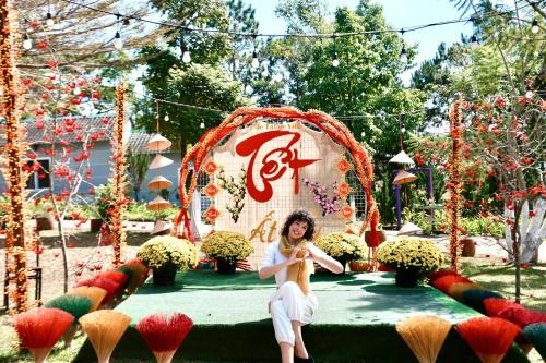 a woman sitting in front of a display of flowers at JE T'AIME VILLA - Khu nghỉ dưỡng nhà vườn nằm giữa thiên nhiên bao la hoa cỏ in Bao Loc