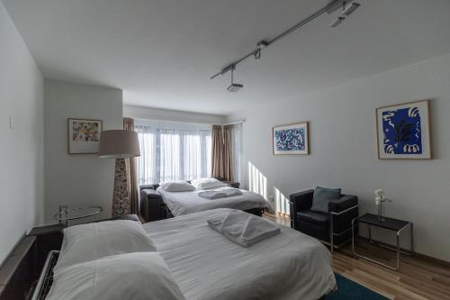 チューリッヒにある2BR flat close to lake, opera and city center - SF10のベッド2台と椅子があるホテルの部屋