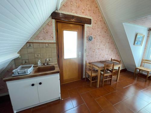 - une cuisine mansardée avec un évier et une table dans l'établissement Loctudy T2 vintage terrasse vue mer, à Loctudy