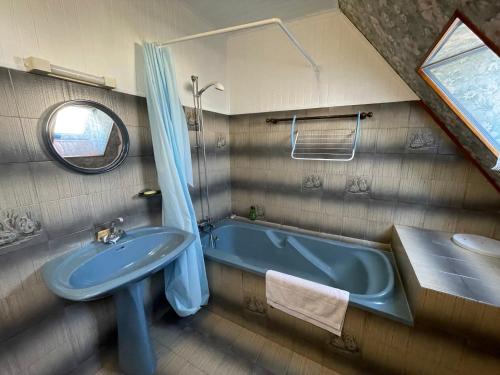 La salle de bains est pourvue d'une baignoire bleue et d'un lavabo. dans l'établissement Loctudy T2 vintage terrasse vue mer, à Loctudy