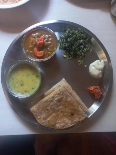a plate of food with soup and a tortilla and dip at Juis Homestay Near Beach Property in Malvan
