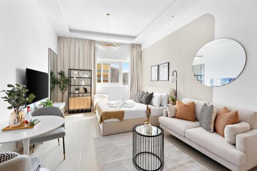 a white living room with a couch and a table at Silkhaus Vacation Homes New studio in Silicon Oasis ASB Tower in Dubai